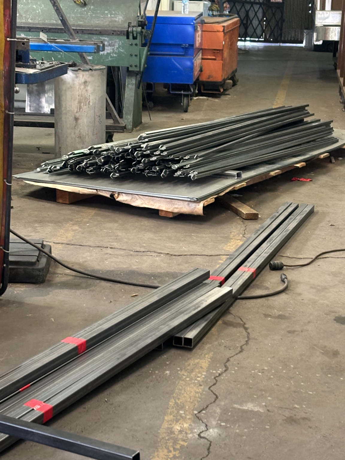 Batch of pressed steel pickets and bundled square tubing in the shop