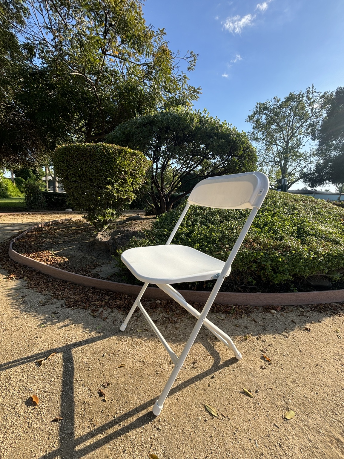 White folding chair with a contoured seat, backrest, and folding metal frame