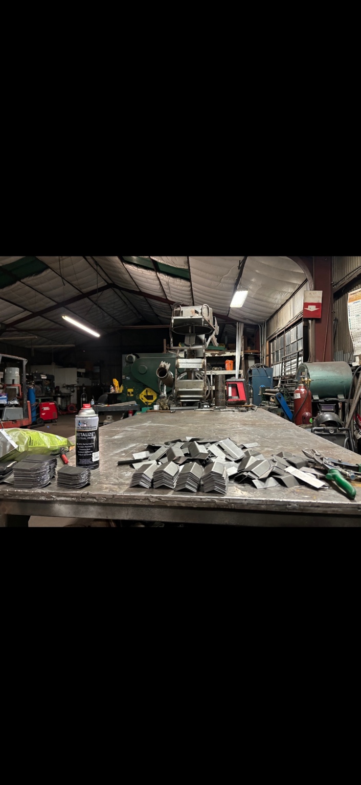 Stacks of cut and bent steel pieces on the workbench inside the Wolf Pack shop